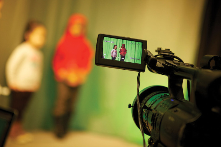 Pupils recording a scene in front of a green screen